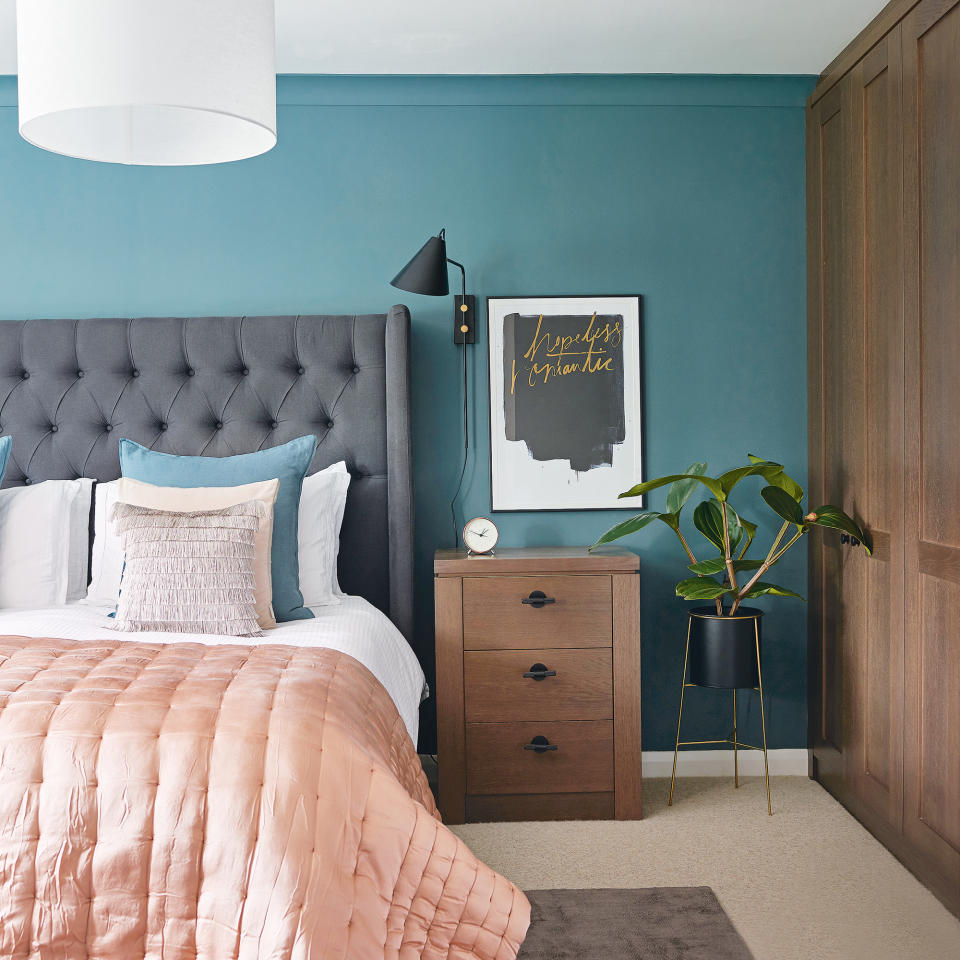 Teal bedroom with grey headboard and pink throw