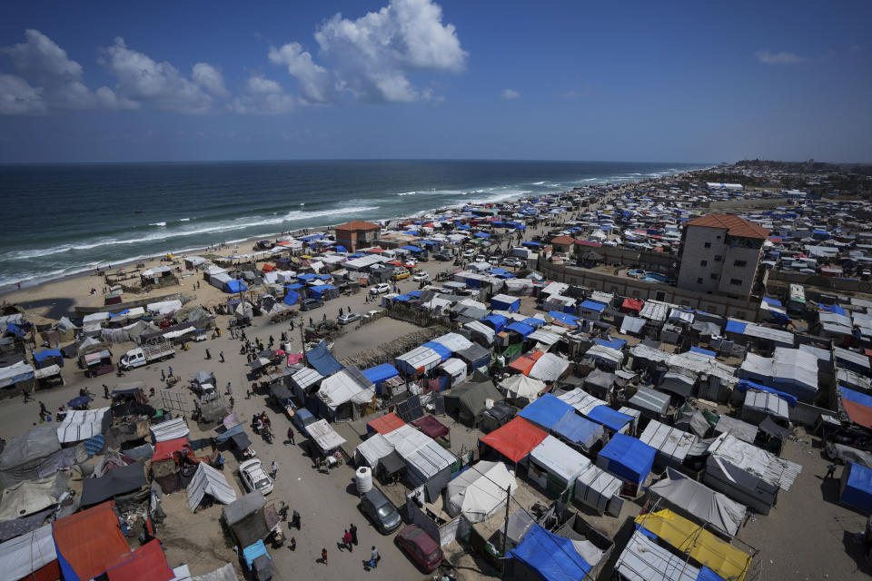 Palestinians displaced by the Israeli air and ground offensive on the Gaza Strip walk through a makeshift tent camp in Deir al Balah, Gaza, Sunday, May 12, 2024. (AP Photo/Abdel Kareem Hana)