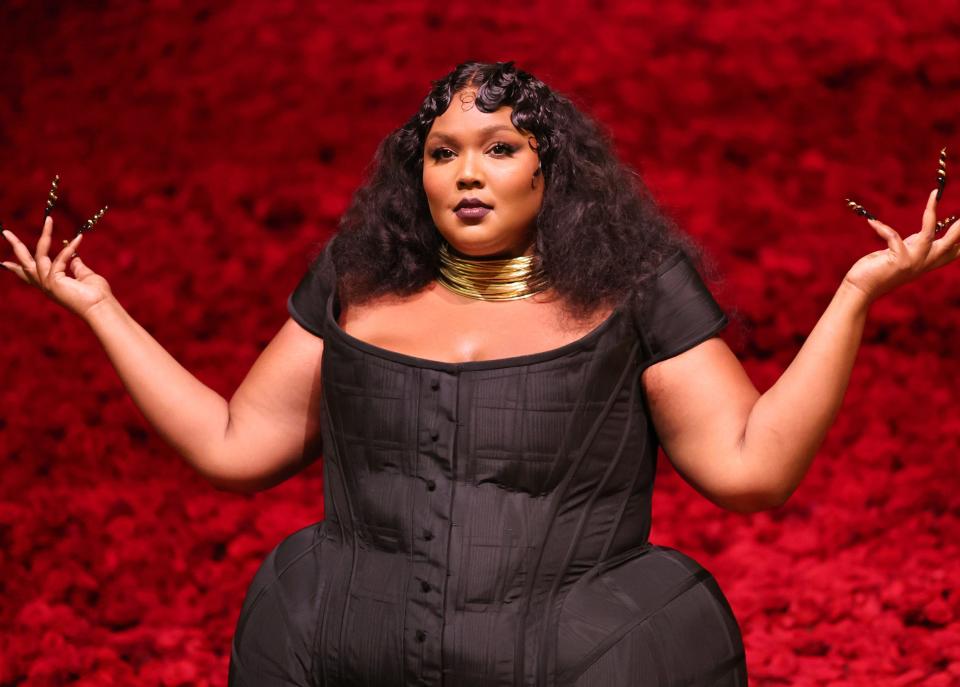 Lizzo holding her hands up as if to say "What?"