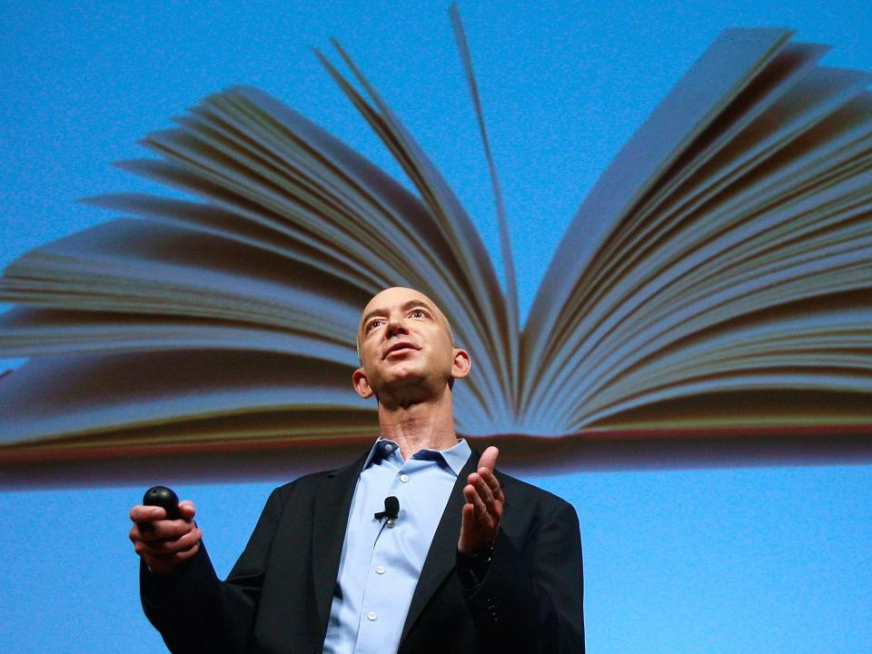 Amazon founder and chair Jeff Bezos pictured here in front of a giant image of a book.