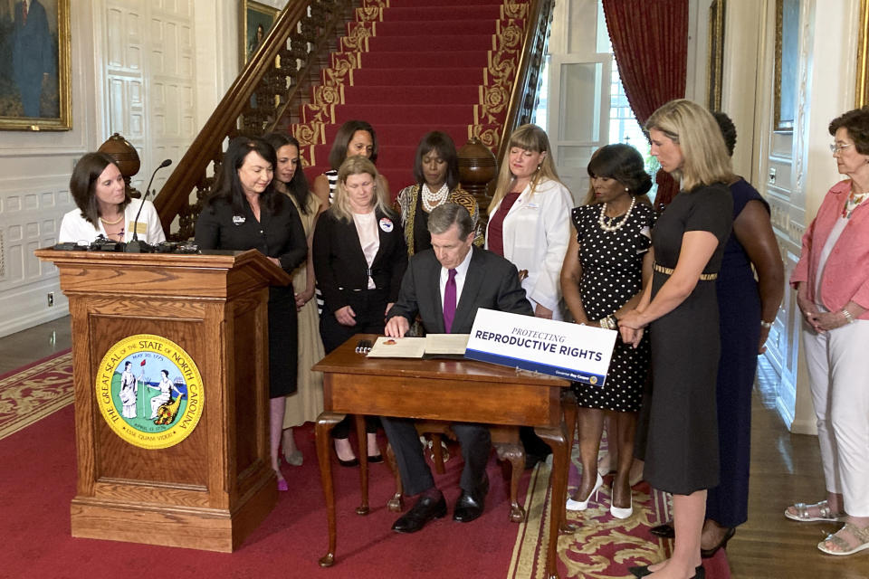 North Carolina Democratic Gov. Roy Cooper signs an executive order designed to protect abortion rights in the state at the Executive Mansion in Raleigh, N.C. on Wednesday, July 6, 2022. The order in part prevents the extradition of a woman who receives an abortion in North Carolina but may live in another state where the procedure is barred. (AP Photo/Gary D. Robertson).