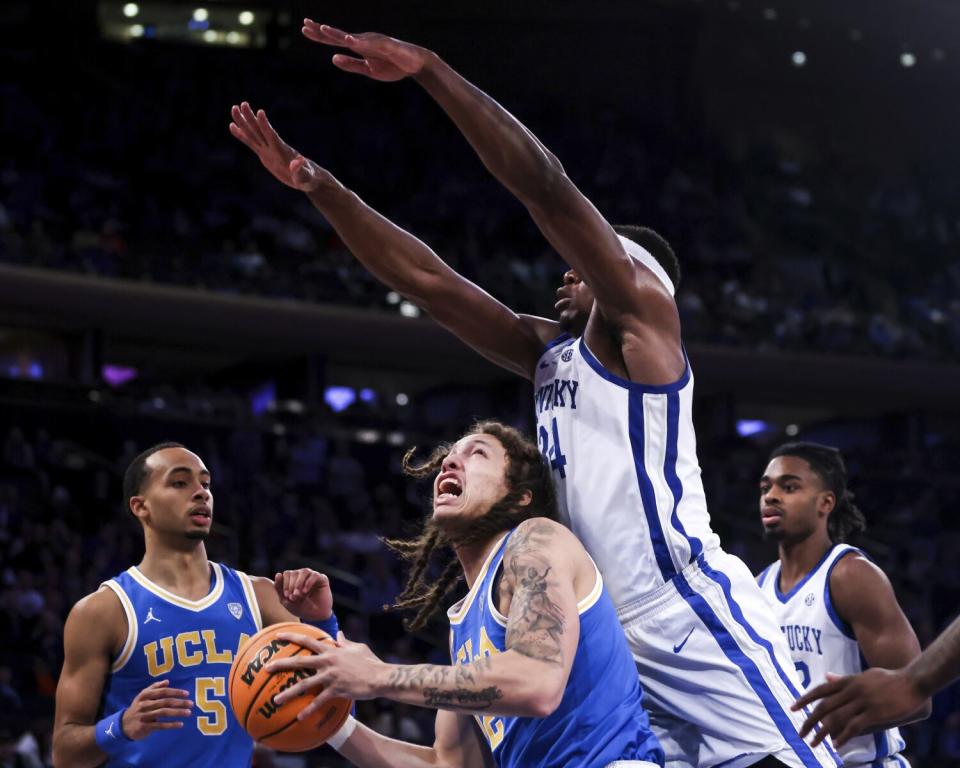 UCLA forward Mac Etienne attempts to shoot past Kentucky forward Oscar Tshiebwe.