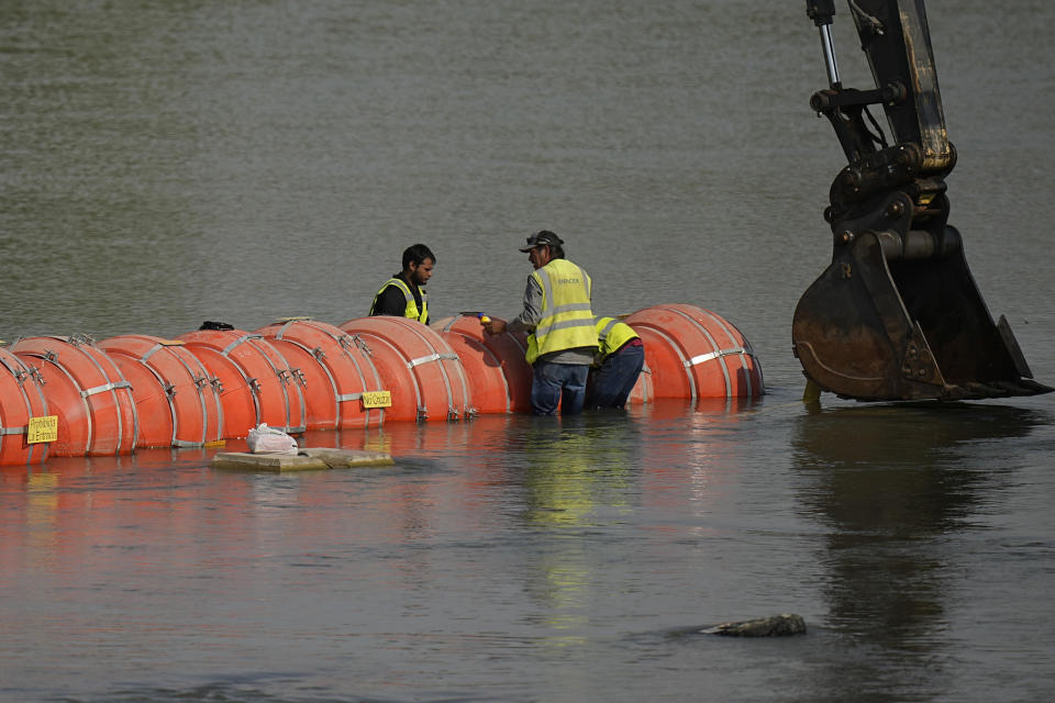 Workers make adjustments to buoys being used as a barrier along the Rio Grande, Monday, Aug. 21, 2023, in Eagle Pass, Texas. (AP Photo/Eric Gay)