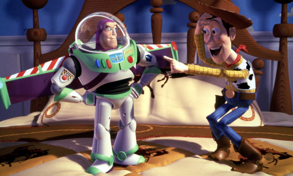 Buzz Lightyear with his wings out and Woody pointing at him and laughing