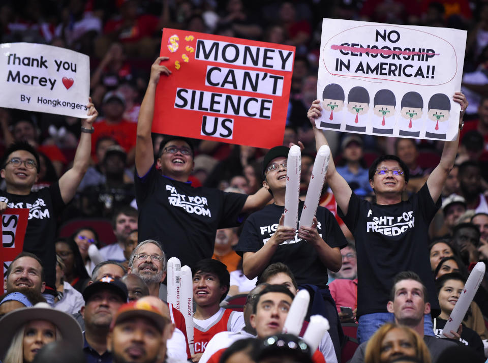 Fans hold signs about Hong Kong during the second half of an NBA basketball game between the Houston Rockets and the Milwaukee Bucks, Thursday, Oct. 24, 2019, in Houston. (AP Photo/Eric Christian Smith)
