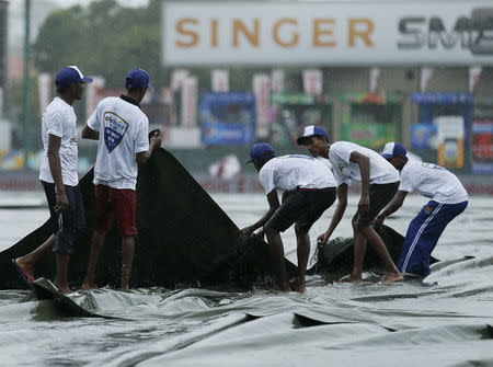 Ground workers pull the covers to cover the ground as the match was stopped due to rain, on the first day of third and final test cricket match between India and Sri Lanka in Colombo August 28, 2015. REUTERS/Dinuka Liyanawatte