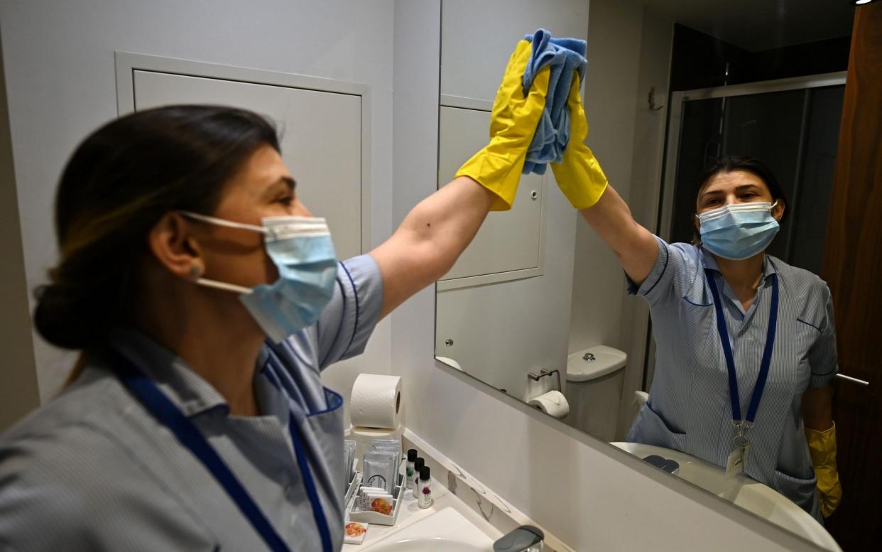 A member of staff cleans surfaces as she prepares a room for a guest at a hotel being used for quarantining passengers near Heathrow - Ben Stansall/AFP via Getty Images