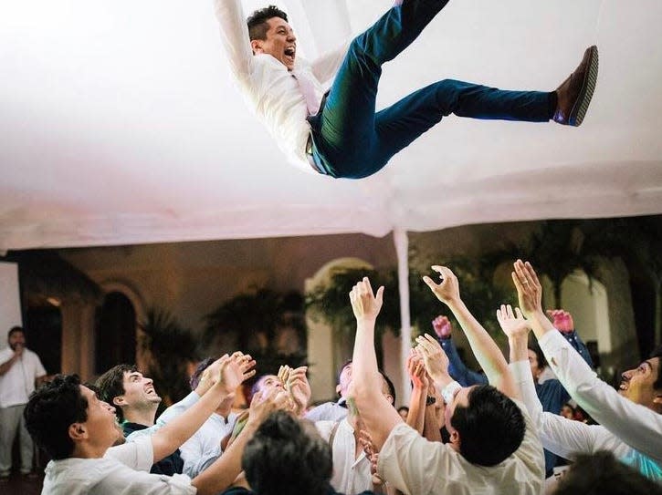 groom being tossed in the air by the crowd at a wedding reception