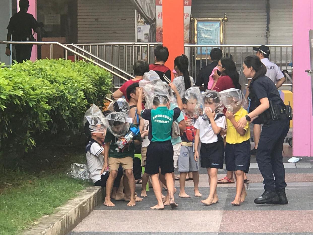 A group of schoolchildren wearing smoke hoods after a fire broke out at Block 720 Ang Mo Kio Ave 6. PHOTO: Daniel Young/Yahoo News Singapore