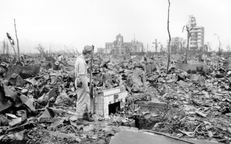 A man stands next to a tiled fireplace where a house once stood in Hiroshima - AP Photo/Stanley Troutman, Pool, File