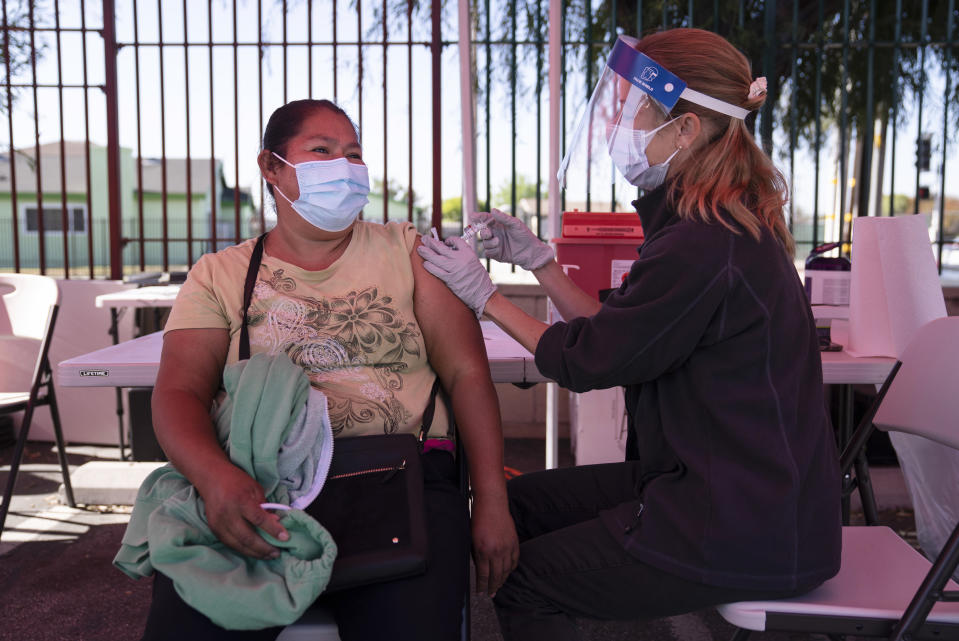 Juanita Ortega, left, receives the Johnson & Johnson's COVID-19 vaccine from registered nurse Anne-Marie Zamora at a Cedars-Sinai sponsored pop-up vaccine clinic at the Watts-Willowbrook Boys & Girls Club in Los Angeles, Wednesday, April 28, 2021. California, swimming in vaccine, is in a far different place than it was just weeks ago when simply scoring an appointment was cause for celebration. Today, Los Angeles, San Diego and other populous counties are advertising that anyone can walk in for a shot and the state is texting reminders that plenty of appointments are available. (AP Photo/Jae C. Hong)