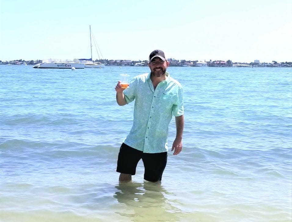 Wade Tatangelo enjoys a beer while cooling off in the Sarasota Bay waters off Bayfront Park in downtown Sarasota.