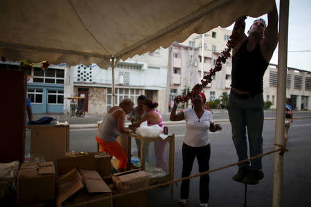 People decorate a shop at an open air state-run market in Havana April 8, 2016. REUTERS/Alexandre Meneghini