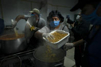 Cooks prepare pasta at a soup kitchen at the San Cayetano church in Jose Leon Suarez neighborhood on the outskirts of Buenos Aires, Argentina, March 31, 2020. The Argentine government said Tuesday that the number of people requesting food assistance has increased following the lockdowns that have left many people unable to work amid the pandemic. (AP Photo/Victor R. Caivano)