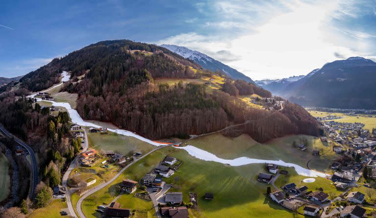 Una vista general muestra una pista de esquí en medio de áreas verdes en Schruns, Austria. Al igual que otras partes de Europa, Austria ha experimentado temperaturas relativamente cálidas durante la última semana. (DIETMAR STIPLOVSEK / APA / AFP)