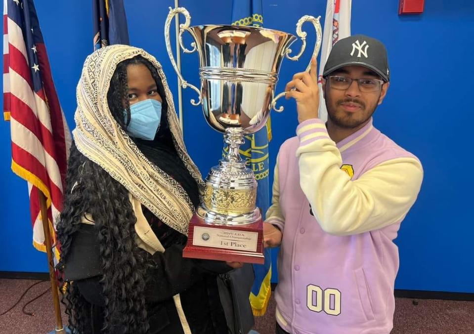 Eli Louis and Akif Choudhury hoist the trophy after winning CEDA Nationals for Binghamton University's speech and debate team.
