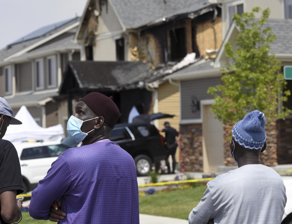 Amadou Deh stands in front of the remnants of a house fire that killed five people in suburban Denver on Wednesday, Aug. 5, 2020. Three people escaped the fire by jumping from the home's second floor. Investigators believe the victims were a toddler, an older child and three adults. Authorities suspect was intentionally set. (AP Photo/Thomas Peipert)