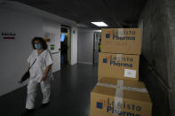 A medical worker walks past covid kit boxes in the Wizink Center, currently used for COVID-19 vaccinations in Madrid, Spain, Wednesday, Dec. 1, 2021. Health authorities in the Spanish capital have confirmed a second case of the omicron coronavirus variant in a 61-year-old woman who had returned from a trip to South Africa on Monday. (AP Photo/Paul White)