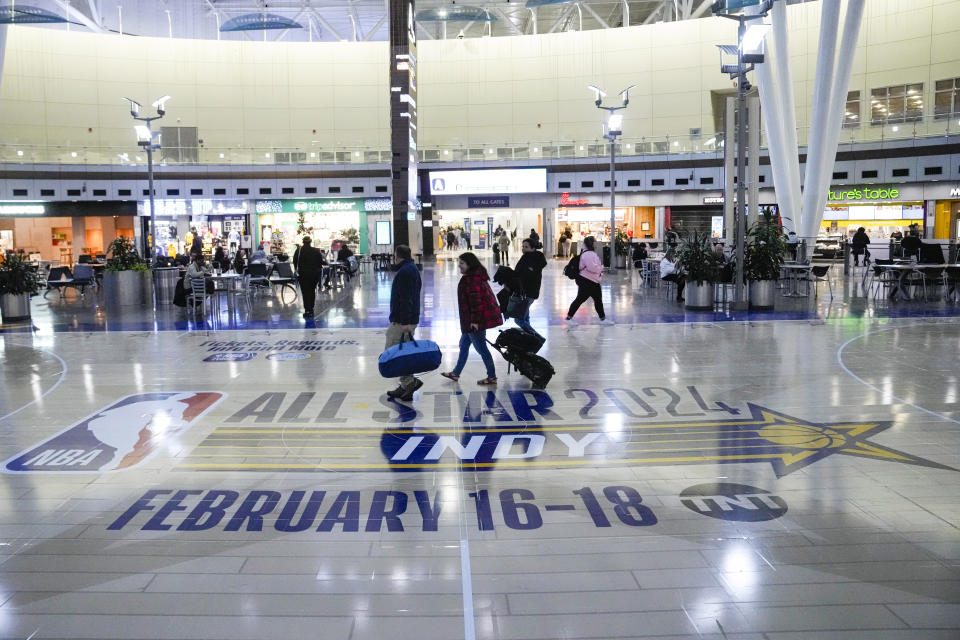 Travelers using Indianapolis International Airport make their way across a replica of the court that will be use for the NBA All-Star game Thursday, Jan. 18, 2024. Authorities have created a full-size replica basketball court with two baskets, one equipped with a short clock, to promote Indy's first All-Star Game since 1984. (AP Photo/Michael Conroy)