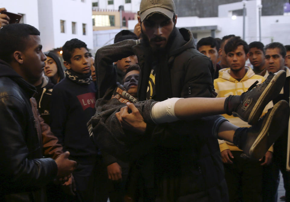 A man helps a wounded youth, who was shot by Israeli troops during a protest at the Gaza Strip's border with Israel, into the treatment room of Shifa hospital in Gaza City, Friday, March 8, 2019. (AP Photo/Adel Hana)