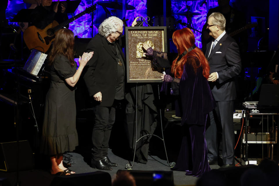 Wynonna Judd, second from the right, touches the plaque as sister Ashley Judd, left, Ricky Skaggs, and MC Kyle Young CEO of the Country Music Hall of Fame & Museum look on during the Medallion Ceremony at the Country Music Hall of Fame on Sunday, May 1, 2022, in Nashville, Tenn. (Photo by Wade Payne/Invision/AP)