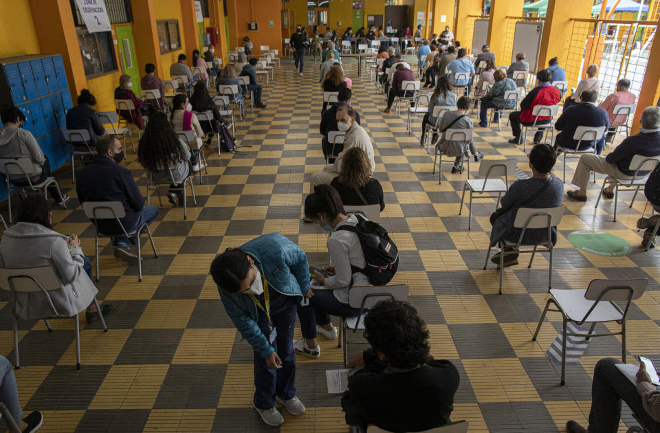 A healthcare worker checks on people under observation after receiving a dose of the Sinovac COVID-19 vaccine at a makeshift vaccination site in the Jose Toribio Medina public school, in Santiago, Chile, Tuesday, March 16, 2021. (AP Photo/Esteban Felix)