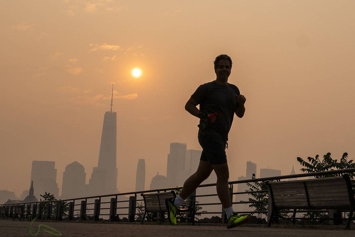 The One World Trade Center and the New York skyline is seen in the background as a man jogs through the Liberty State Park while the smoke from Canada wildfires covers the Manhattan borough on Thursday, June 8, 2023, in New Jersey.