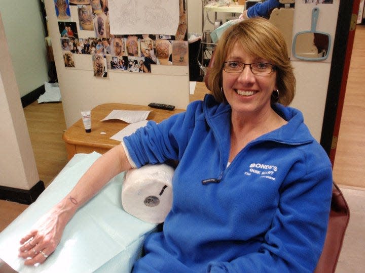 Karen Mansker shows off her ichthys tattoo at Rick's Tattoos, as seen, April 2011, in Green Bay, Wis.