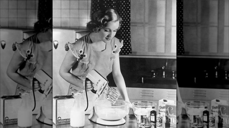 Black and white photo of housewife making whipped cream with hand mixer