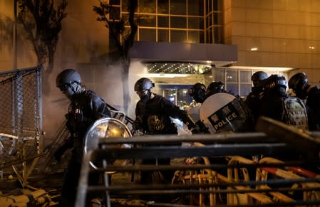 Police officers walk through a barricade put up by demonstrators during a protest in Hong Kong