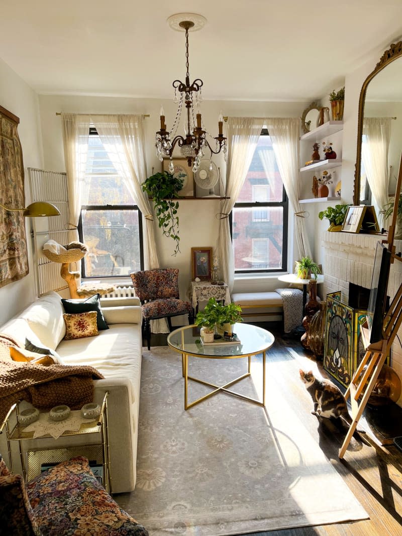 A living room with a white couch, glass coffee table, and many decorative items.