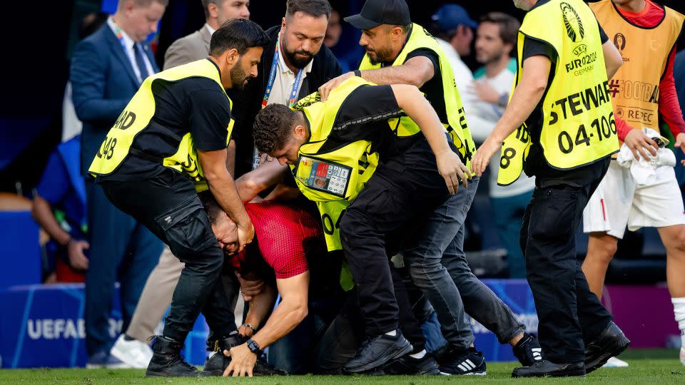 A pitch invader is carted off the pitch during the match. - Rico Brouwer/Soccrates Images/Getty Images