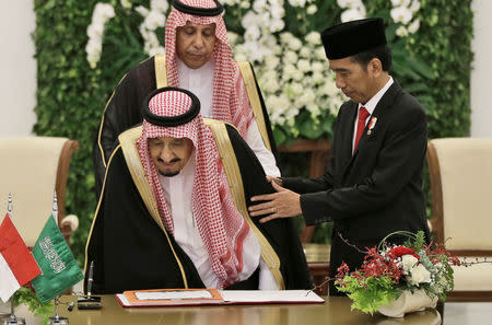 Indonesian President Joko Widodo assists Saudi Arabia's King Salman as he takes his seat to sign the guest book at the Presidential Palace in Bogor, West Java, Indonesia March 1, 2017. REUTERS/Achmad Ibrahim