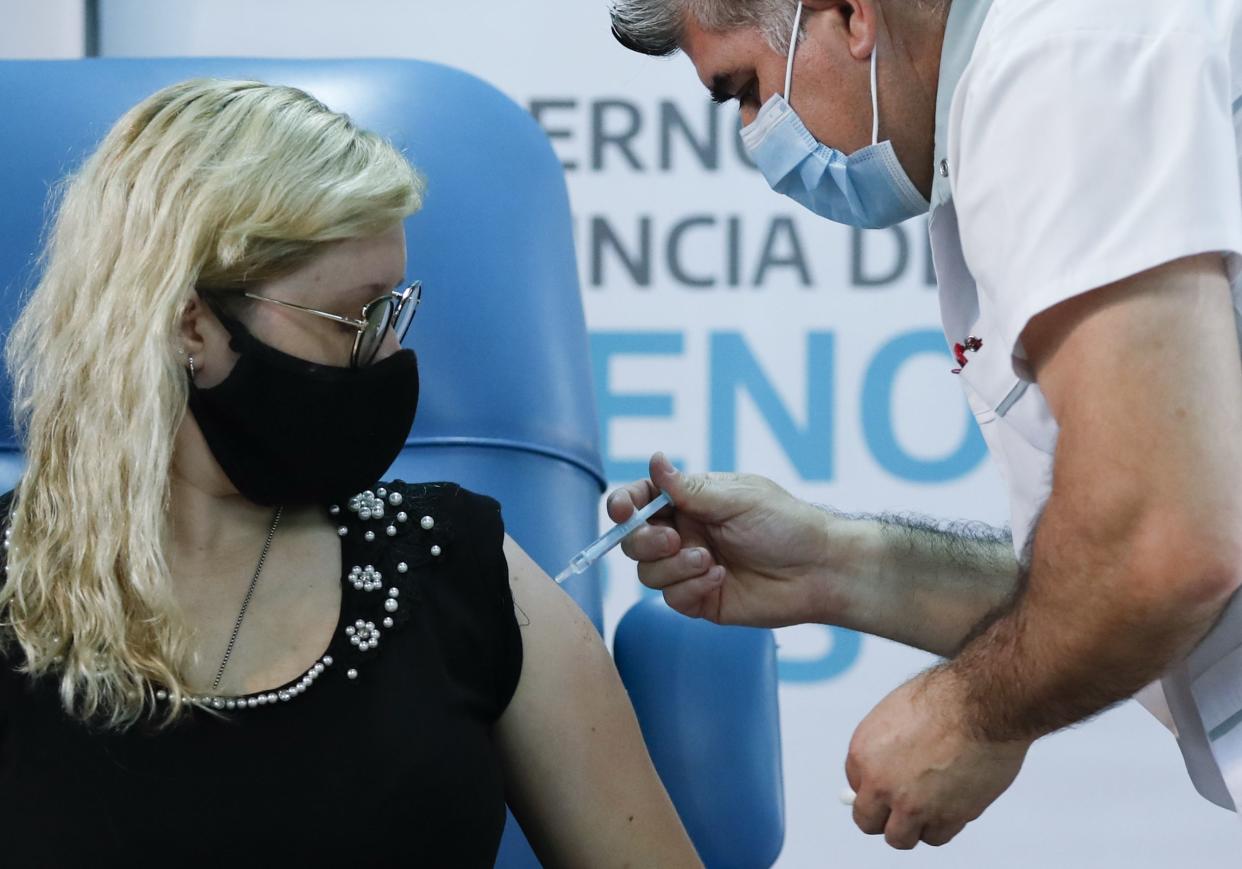 Nurse Gustavo Rodriguez gives nurse Florencia Arroyo a shot of Russia's Sputnik V vaccine for COVID-19 at Dr. Pedro Fiorito Hospital in Avellaneda, Argentina on Tuesday, Dec. 29, 2020.