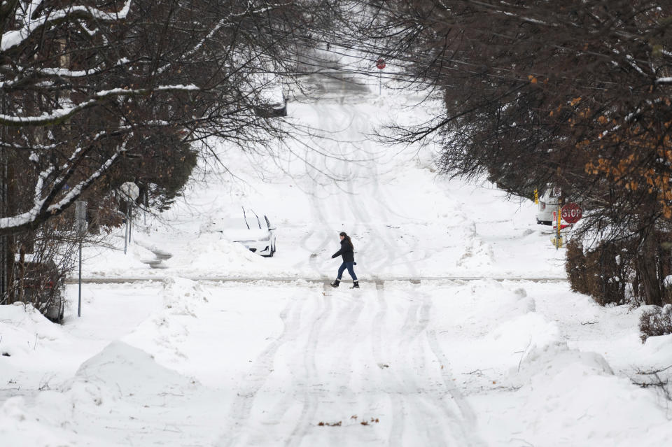 A person makes their way through the Sandy Hill neighborhood of Ottawa, on Friday, Dec. 23, 2022. Environment Canada has issued a winter storm warning for the region which is calling for flash freezing, icy and slippery surfaces, wind gusts and chills. (Spencer Colby /The Canadian Press via AP)