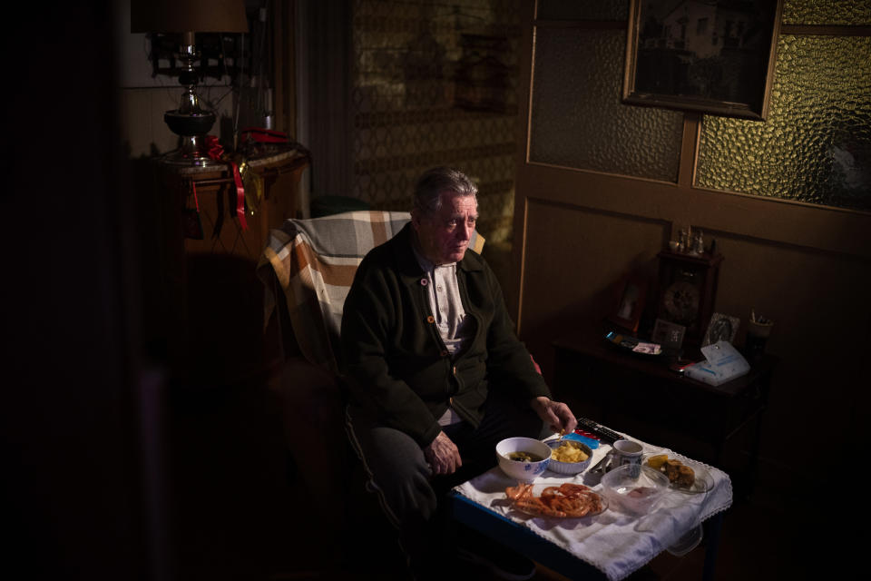 Álvaro Puig Moreno watches television while eating a his Christmas Eve dinner at his home in Barcelona, Spain, Thursday, Dec. 24, 2020. "The solitude gets to me these days, I often feel depressed," Puig said. "These holidays, instead of making me happy, make me sad. I hate them. Most of family has died, I am one of the last ones left. I will spend Christmas at home alone because I don't have anyone to spend them with."(AP Photo/Emilio Morenatti)