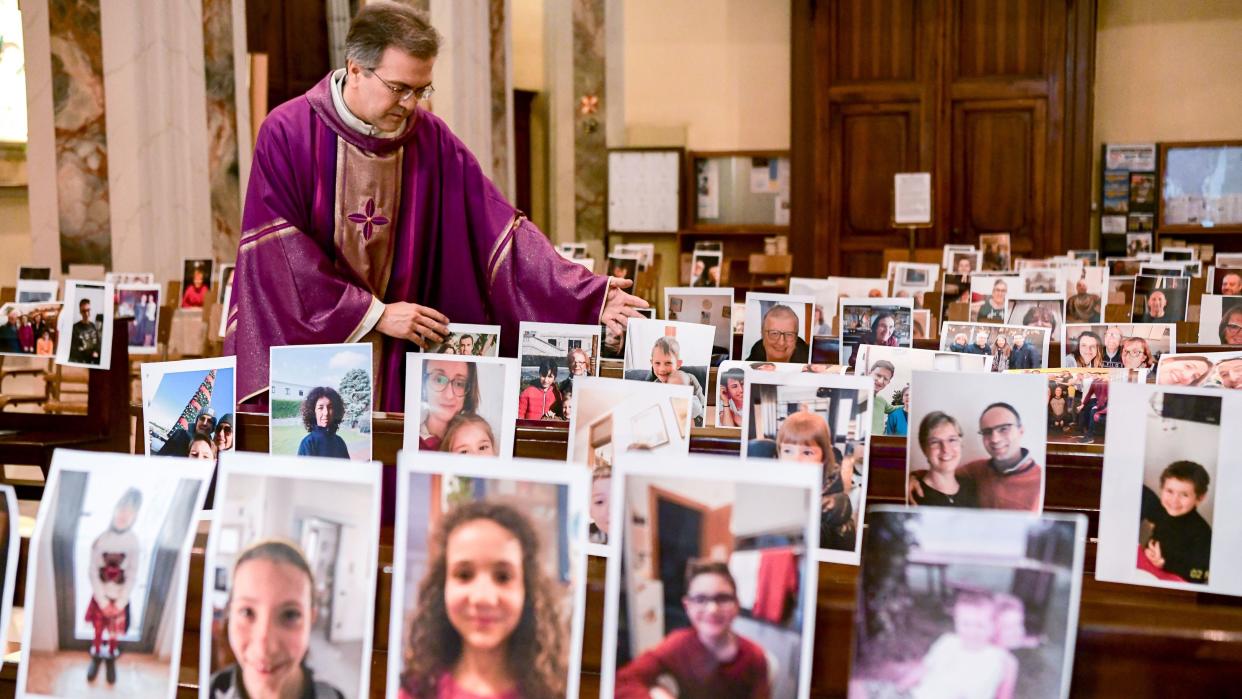 Don Giuseppe Corbari, parson of the Church of Robbiano, adjusts photos of his congregation at empty pews before celebrating Sunday Mass in Giussano, Italy, on March 22, 2020.&nbsp; (Photo: PIERO CRUCIATTI via Getty Images)