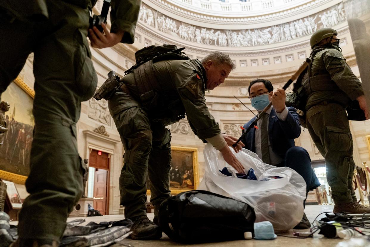 Rep. Andy Kim, D-N.J., helps ATF police officers clean up debris and personal belongings strewn across the floor of the Rotunda in the early morning hours of Thursday, Jan. 7, 2021, after protesters stormed the Capitol in Washington on Wednesday.