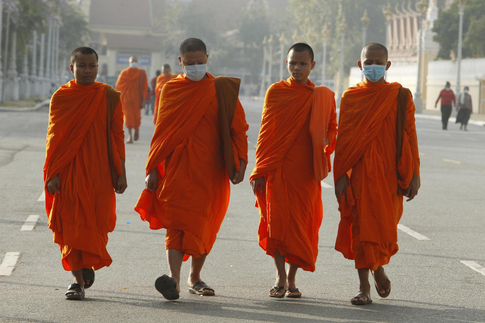 Buddhist monks wear masks as they walk near Royal Palace in Phnom Penh, Cambodia, Tuesday, Jan. 28, 2020. China on Tuesday reported 25 more deaths from a new viral disease, as the U.S. government prepared to fly Americans out of the city at the center of the outbreak. (AP Photo/Heng Sinith)