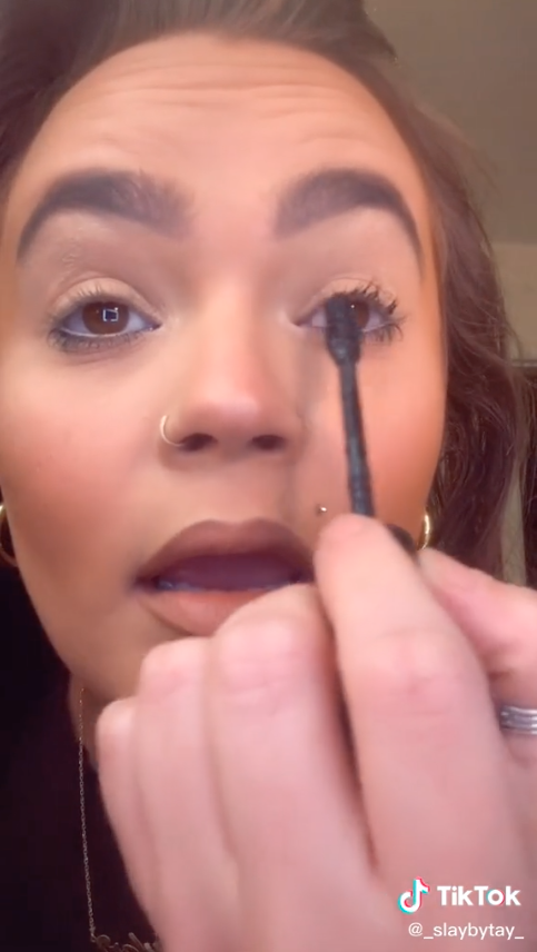 Woman using tip of Fenty Beauty mascara to apply it