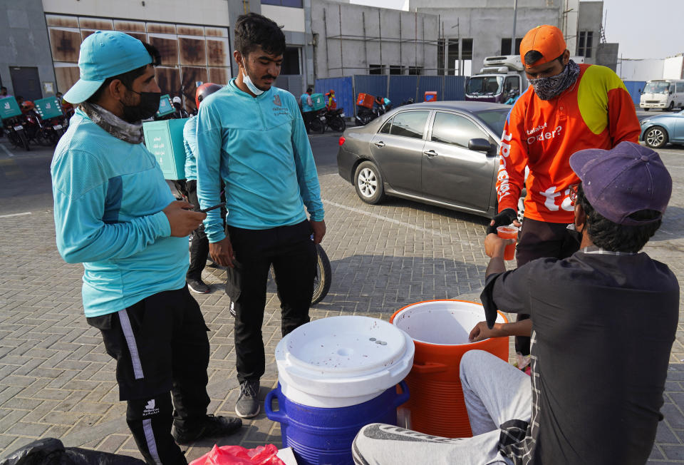 Motorcycle delivery drivers take a break and buy juice, in Dubai, United Arab Emirates, Thursday, Sept. 9, 2021. Advocates and workers say that casualties among food delivery riders are mounting in the city of Dubai, as the pandemic accelerates a boom in customer demand. “Of course they're getting injured. They're overworked, dehydrated, exhausted,” said Dr. Taimoor Tung at Dubai’s Orthopaedics and Spine Hospital. (AP Photo/Jon Gambrell)