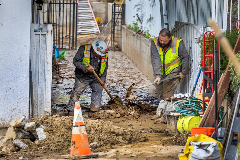 Hacienda Heights, CA - February 08: Workers dig through the mud at one home where multiple mudslides damaged three homes Tuesday on Gotera Dr, in Hacienda Heights Thursday, Feb. 8, 2024. Three homes in Hacienda Heights had to be evacuated Tuesday morning after a major mudslide that occurred around 9:30 a.m after a hillside collapsed into the homes' backyards. A monster storm triggered hundreds of mudslides across Los Angeles County. The city was still working its way through 562 mudslides as of Wednesday evening. (Allen J. Schaben / Los Angeles Times)