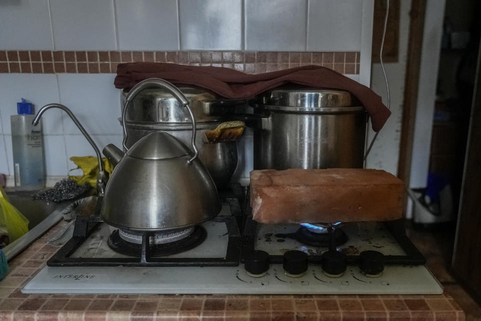 A fire-resistant brick heats on the stove in Larysa Shevtsova's home in in Kherson, Ukraine as the family tries to warm the house on Nov. 26, 2022. When the rectangular block was hot enough, it was carried carefully into the living room and set on top of a Soviet-era space heater that no longer worked. Shevtsova, her husband and two sons, one of them three years old, huddled around the brick for warmth that would last for about 30 minutes. “We use this method to heat the room,” Shevtsova said. “Before that we just froze.” (AP Photo/Sam Mednick)