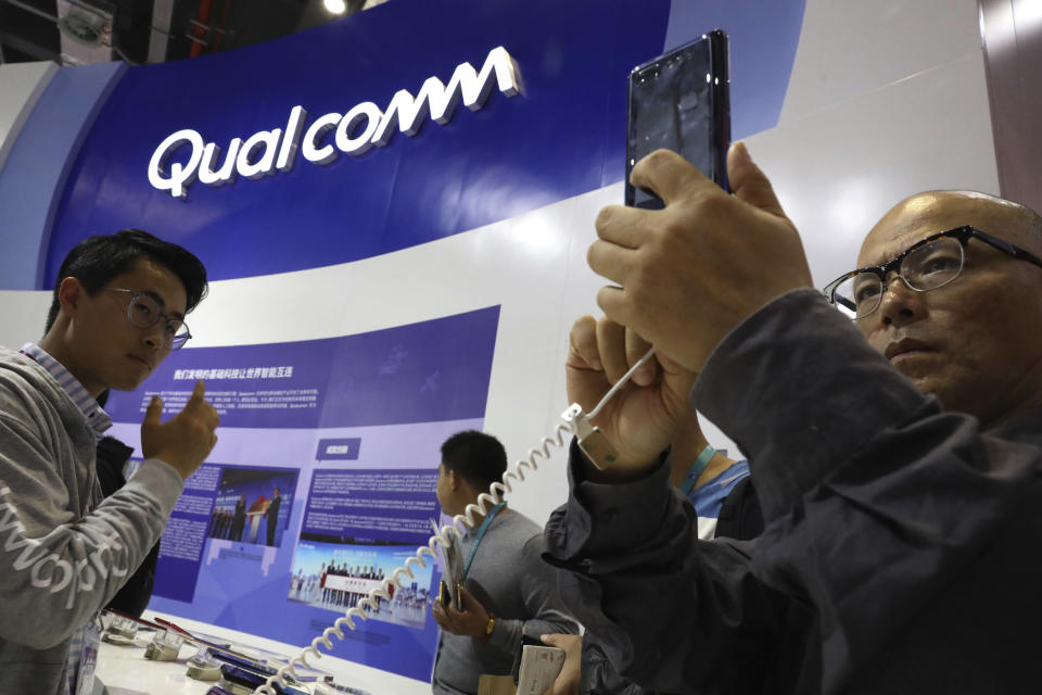Attendees look at the latest technology from Qualcomm at the China International Import Expo in Shanghai, Tuesday, Nov. 6, 2018. Chinese President Xi Jinping has promised to open China's market wider as he opened a trade fair meant to promote the country's image as an importer, but he offered no response to U.S. and European complaints about technology policy and curbs on foreign business. (AP Photo/Ng Han Guan)