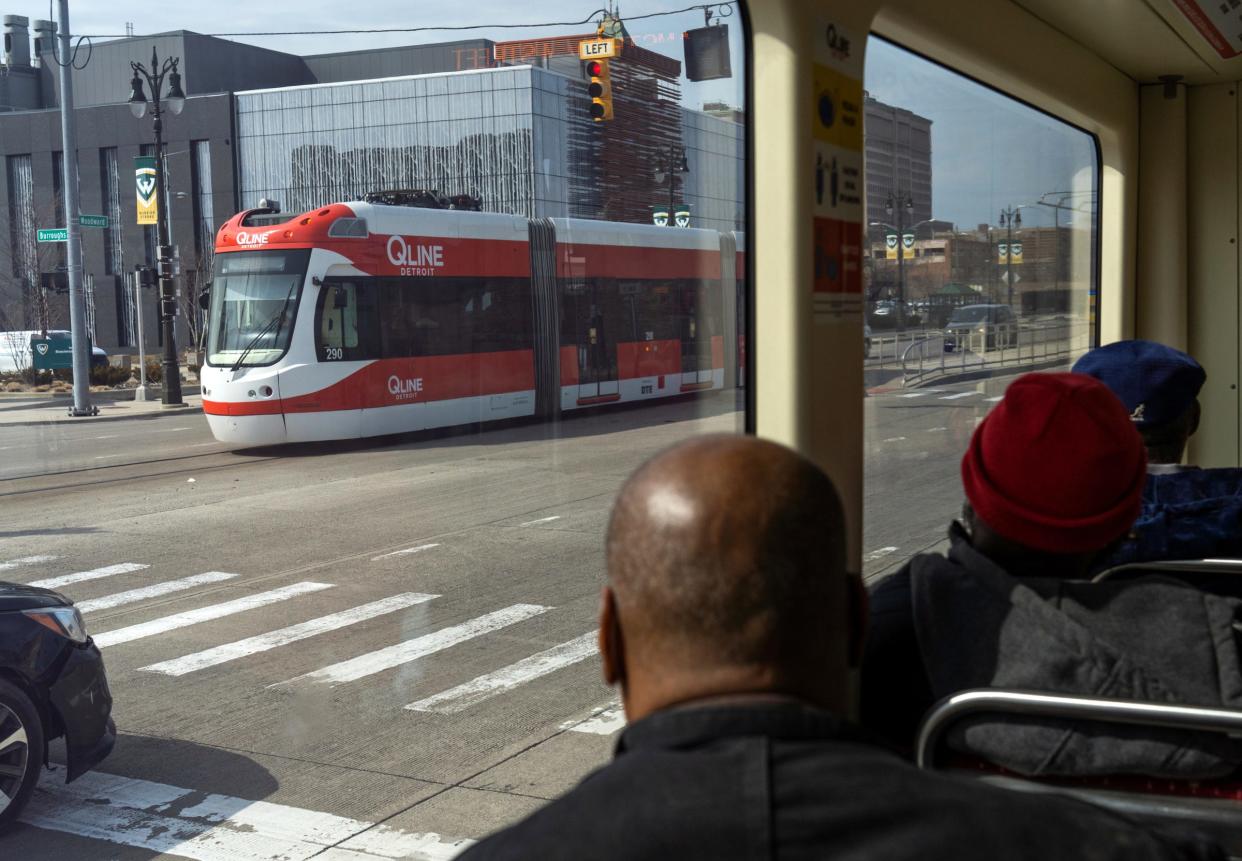 Passengers watch as another QLINE streetcar passes them while riding along Woodward Avenue in Detroit on March 21, 2022.