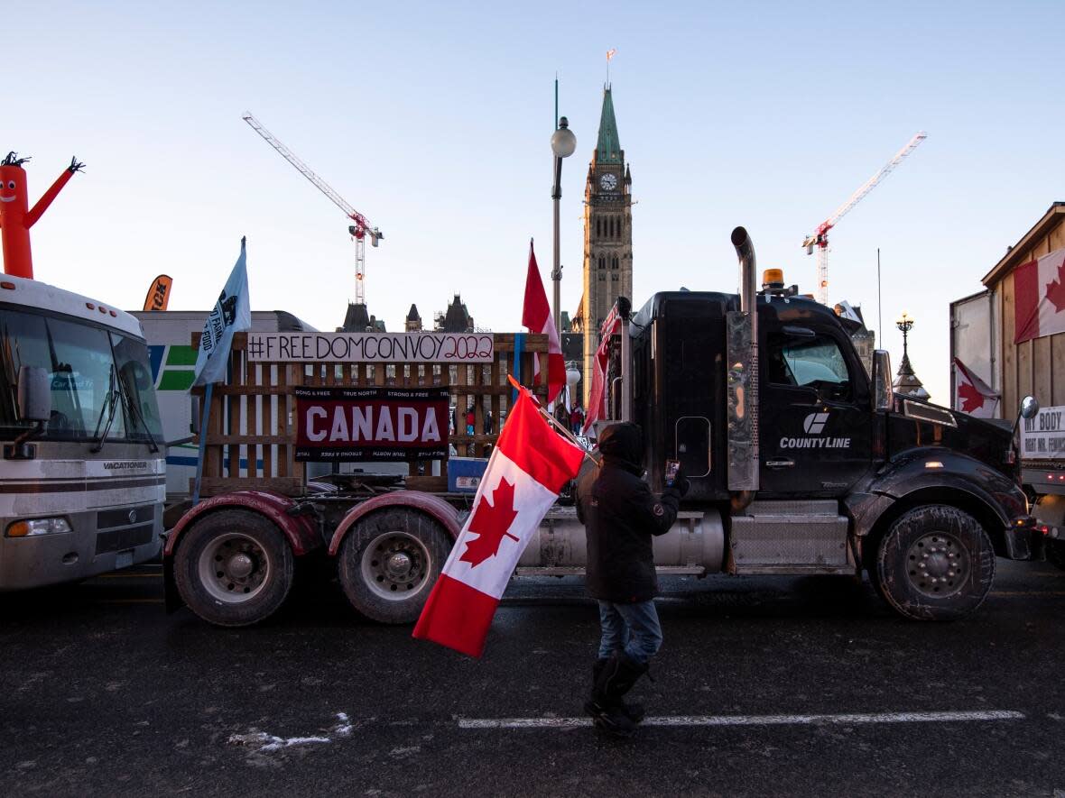 Trucks participating in a cross-country convoy protesting measures taken by authorities to curb the spread of COVID-19 are parked on Wellington Street in front of Parliament Hill in Ottawa, on Friday. (Justin Tang/The Canadian Press - image credit)