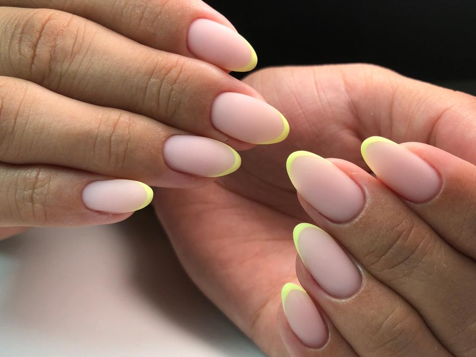 Hands with thin, neon yellow manicure.