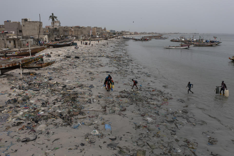 The environmental activist Modou Fall, who many simply call "Plastic Man", walks on Yarakh Beach littered by trash and plastics in Dakar, Senegal, Tuesday, Nov. 8, 2022. In 2020, Senegal passed a law that banned some plastic products. But if the mountains of plastic garbage on this beach are any indication, the country is struggling with enforcement. (AP Photo/Leo Correa)