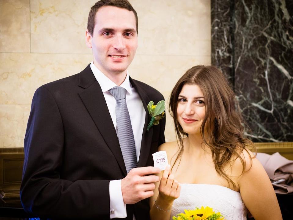 A groom and bride (the author) at New York City's City Hall hold a ticket for their place in line.