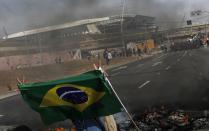 A member of Brazil's Homeless Workers' Movement blocks a road during a protest in front of Sao Paulo's World Cup stadium in this May 15, 2014 file photo. With kickoff two weeks away and tensions simmering over the costs of hosting the month-long soccer event, some are showing their anger by saying they will root against the national team, perhaps Brazil's most prominent symbol on the global stage. REUTERS/Nacho Doce/Files (BRAZIL - Tags: SPORT SOCCER WORLD CUP CIVIL UNREST)